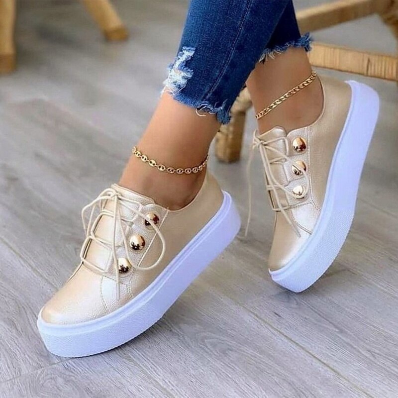 Gold sneakers with white platform soles, gold eyelets. Worn with frayed jeans and anklets.
