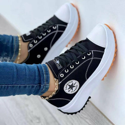 Black and white sneakers with orange soles and star logo, paired with blue jeans.