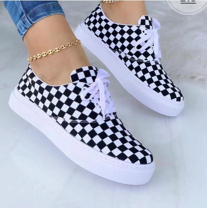 Black and white checkered sneakers with white soles and laces, worn with blue jeans.