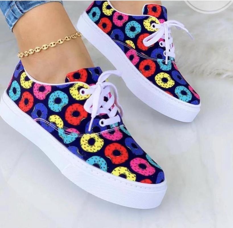 Colorful sneakers with donut patterns, white soles, and laces; worn with a gold ankle bracelet.