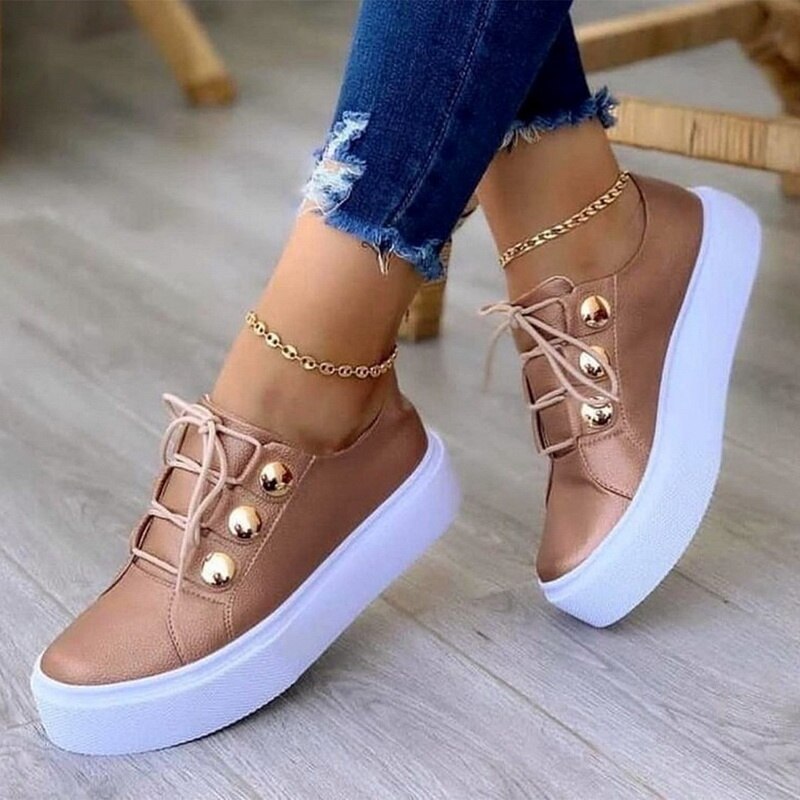 Brown sneakers with gold buttons and white soles, paired with ripped jeans and gold anklet.