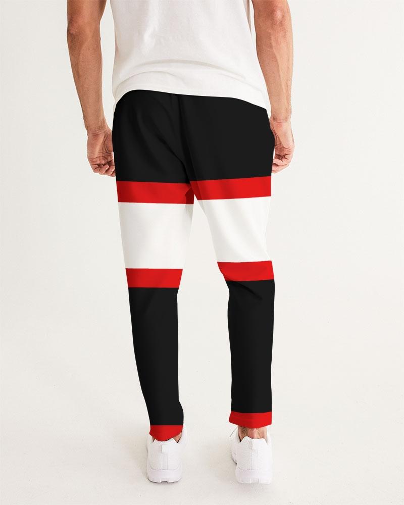Man wearing black pants with red and white horizontal stripes, white top, and white shoes.