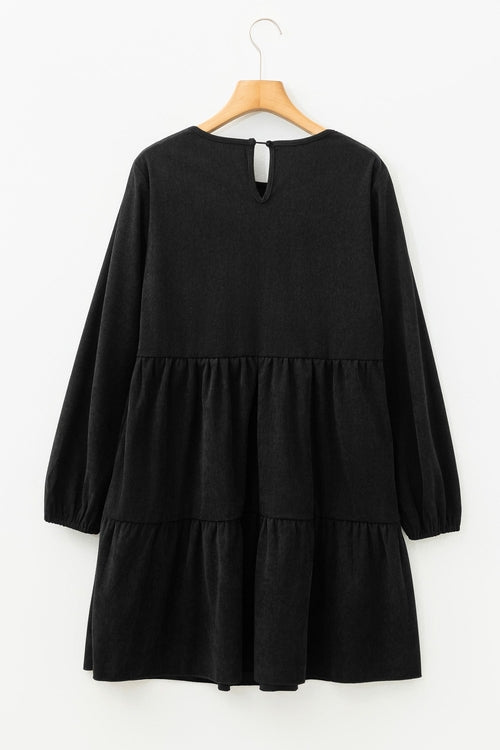 Black long-sleeve dress with tiered skirt on a wooden hanger against a white background.