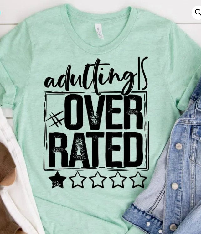 Mint green shirt with bold black text, "Adulting is Overrated," and a denim jacket beside it.