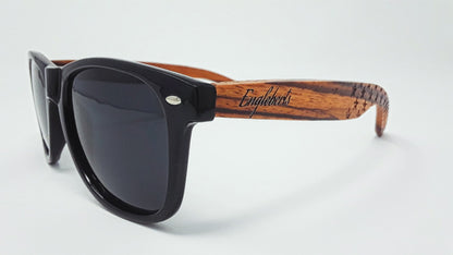 Black sunglasses with dark lenses and brown wood-patterned arms on a white background.