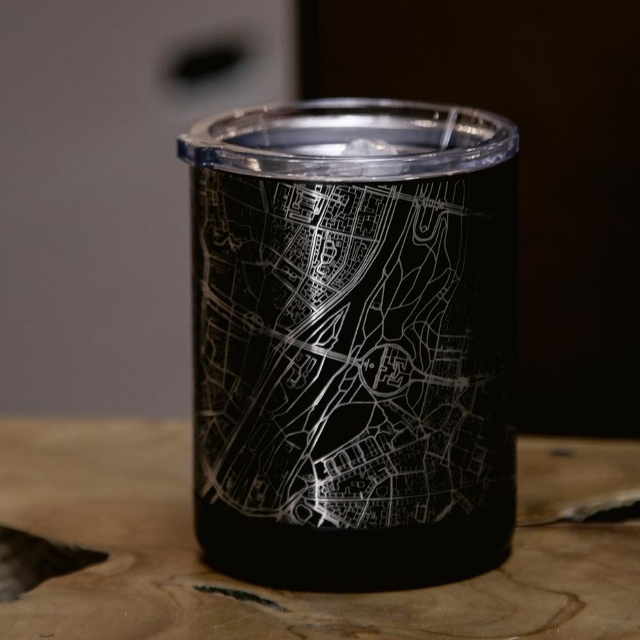 Black tumbler with silver map design on a light wood surface, lid with straw opening.