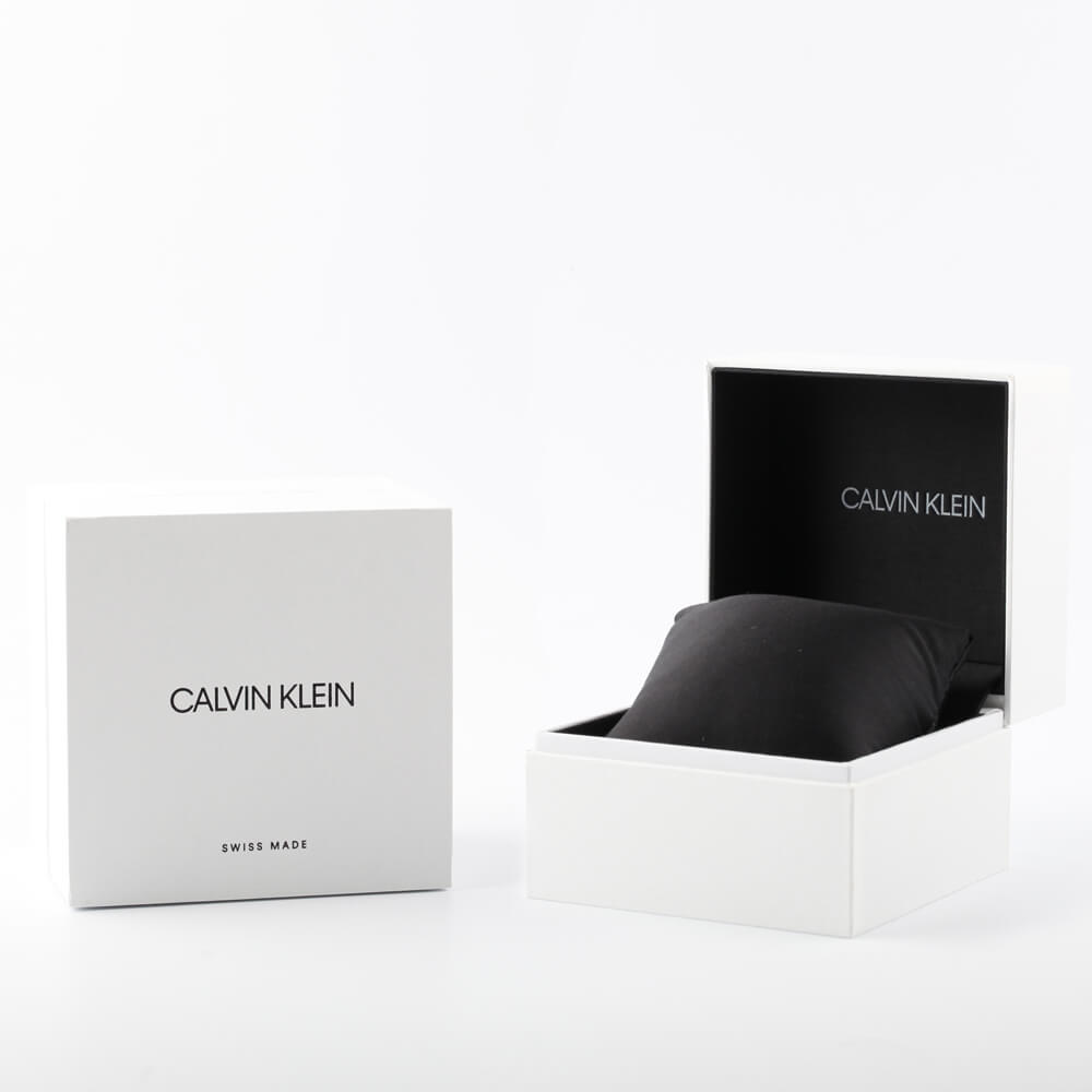 Open white Calvin Klein box with black interior and cushion beside closed box on white background.