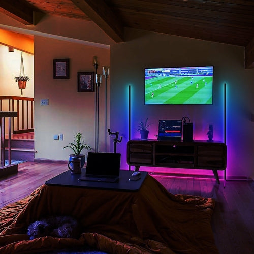 Cozy room with ambient LED lighting, TV showing sports, plants, and a table holding a laptop.