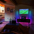 Cozy room with ambient LED lighting, TV showing sports, plants, and a table holding a laptop.