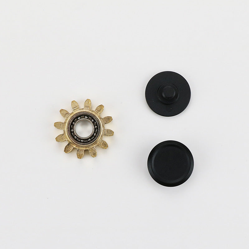 Brass gear with twelve teeth and black discs on a white background.