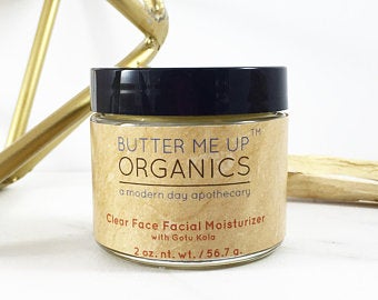 A jar of face moisturizer with a black lid and beige label on a white backdrop.