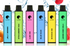 Six colorful vape pens in green, blue, pink, and yellow against a splash of water with fruits.