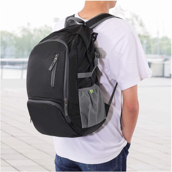 Person in white t-shirt wearing a black backpack with gray zippers and mesh side pocket.