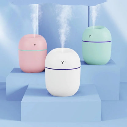 Three pastel humidifiers—pink, white, and mint—release mist on a light blue stepped surface.