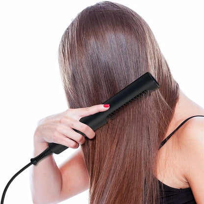 Person straightening long brown hair with a black flat iron, wearing a black top.