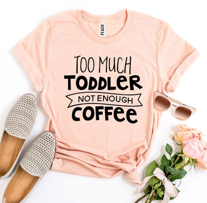 Peach shirt with "Too Much Toddler Not Enough Coffee" text, next to shoes, sunglasses, and roses.