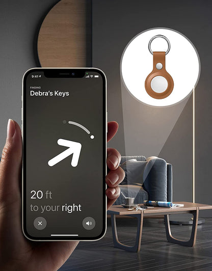Close-up of a phone showing a location screen with an arrow, keys in a leather holder, and a couch.