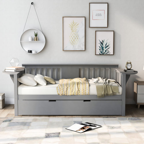 Gray daybed with striped pillows and yellow blanket, surrounded by framed art and a circular shelf.