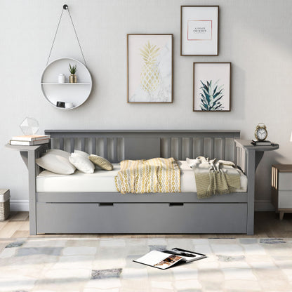 Gray daybed with striped pillows and yellow blanket, surrounded by framed art and a circular shelf.