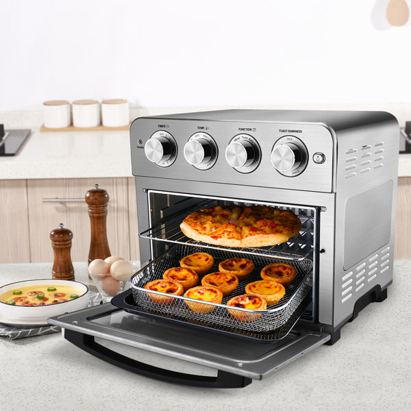 Stainless steel toaster oven with pizza and tarts inside, knobs on top, on a kitchen counter.