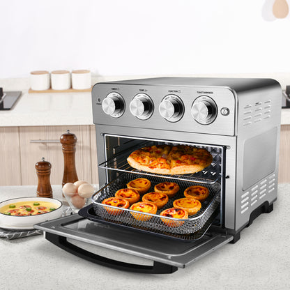 Stainless steel toaster oven with pizza and tarts inside, knobs on top, on a kitchen counter.