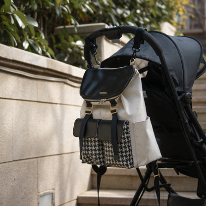 Stroller with a stylish beige and black houndstooth backpack hanging on the handle.
