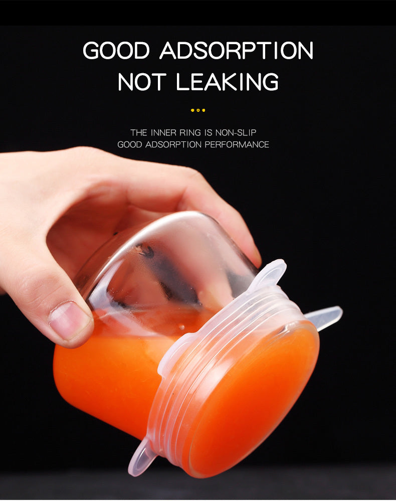 Hand holding a clear jar with an orange liquid and a sealed lid against a dark background.