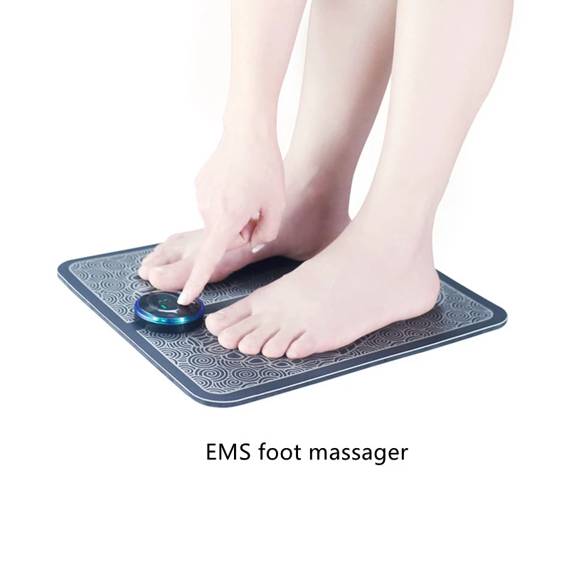 Feet on a black patterned EMS foot massager, with a hand pressing the control button.