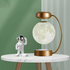 Astronaut figure and moon lamp on round table with green background and bronze stand.