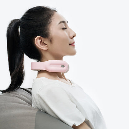 Woman relaxing with a pink neck massager, eyes closed, leaning back on a gray chair, wearing white.