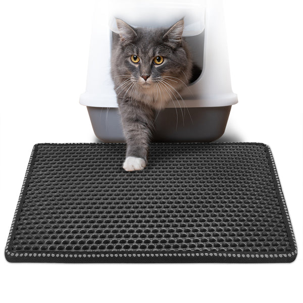 Gray cat exiting litter box onto a black textured mat with circular patterns.