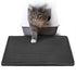 Gray cat exiting litter box onto a black textured mat with circular patterns.