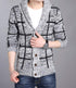 Person wearing a gray checkered cardigan with brown buttons, white shirt, and blue jeans.