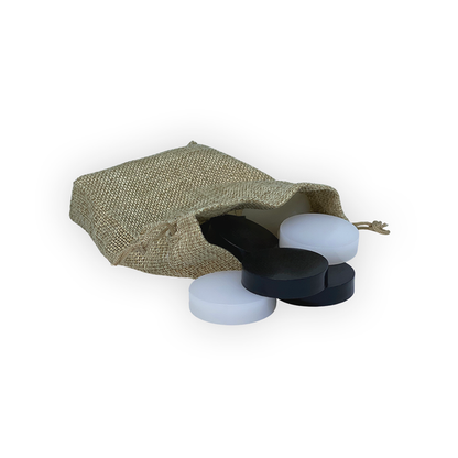 Burlap bag with black and white round pieces spilling out on a white background.