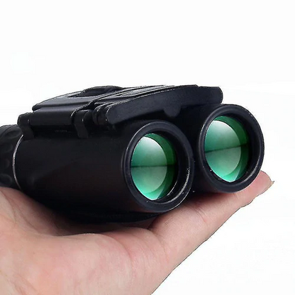 Black binoculars with green lenses held in a person&
