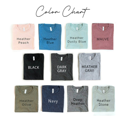 Color chart of folded t-shirts in peach, blue, dusty blue, mauve, black, gray, navy, olive, and stone.