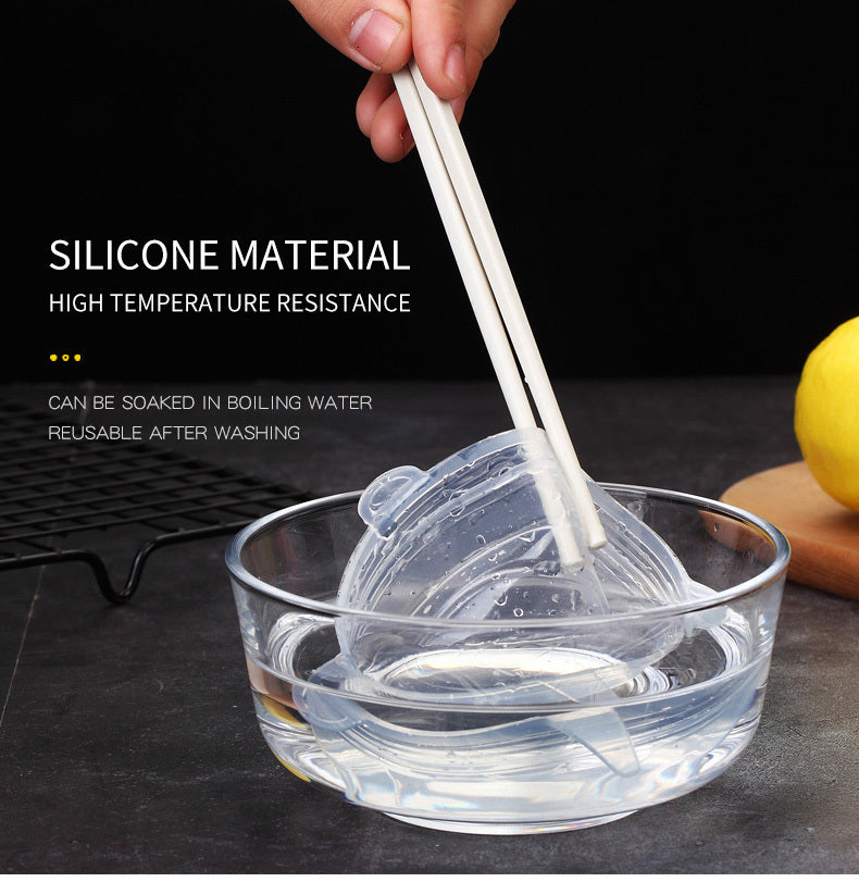 Hand holding chopsticks with silicone mold in clear bowl of water, lemon in background.