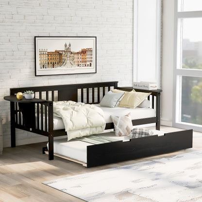 Black daybed with trundle, beige bedding, brick wall, framed art, and sunlight by a large window.