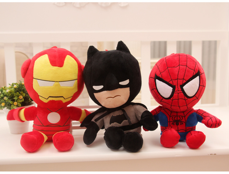 Three plush toys of red and yellow, black and gray, and red and blue sit on a white bench.