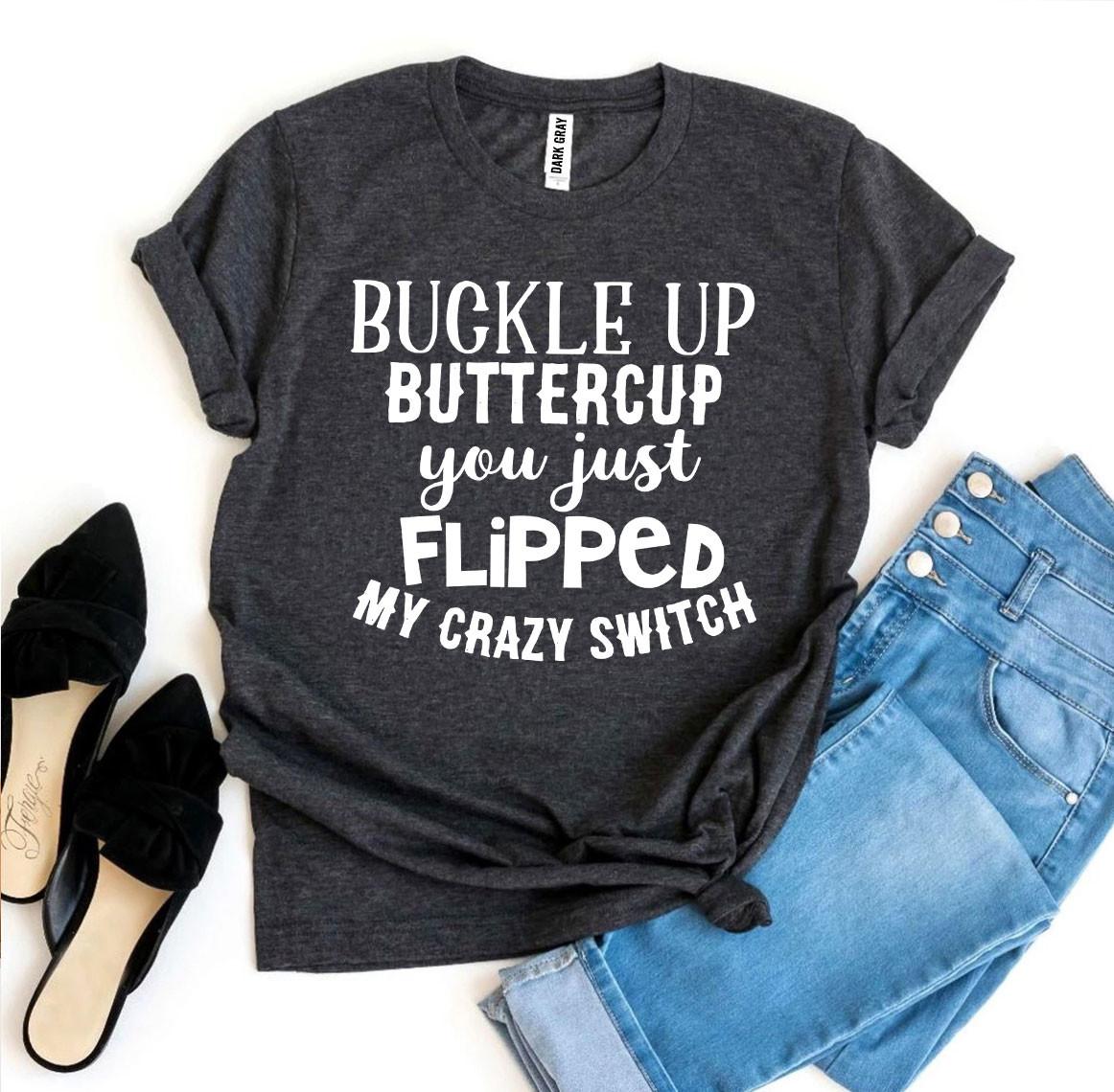Dark gray t-shirt with white text, light blue denim jeans, and black pointed shoes.
