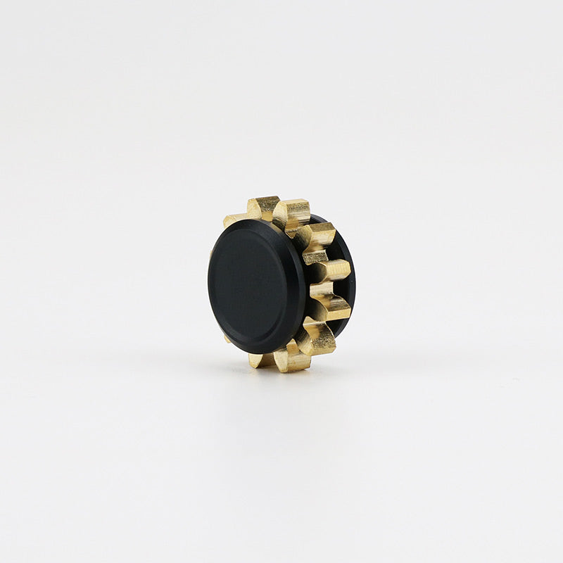 A black circular knob with brass gear-like edges on a white background.