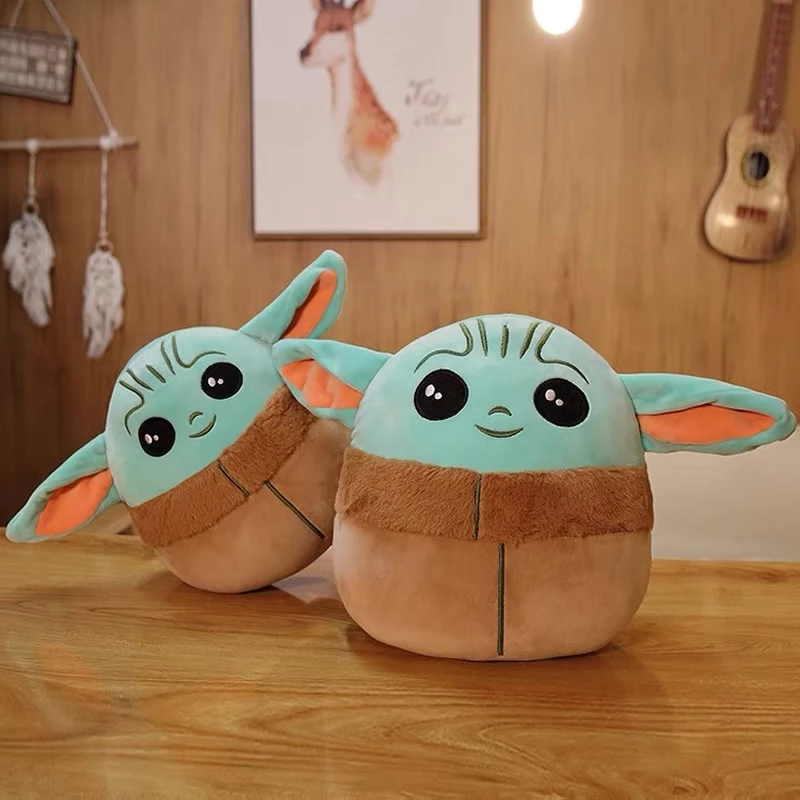 Two plush toys with green faces, large ears, and brown bodies on a wooden table with a warm room setting.