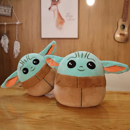 Two plush toys with green faces, large ears, and brown bodies on a wooden table with a warm room setting.
