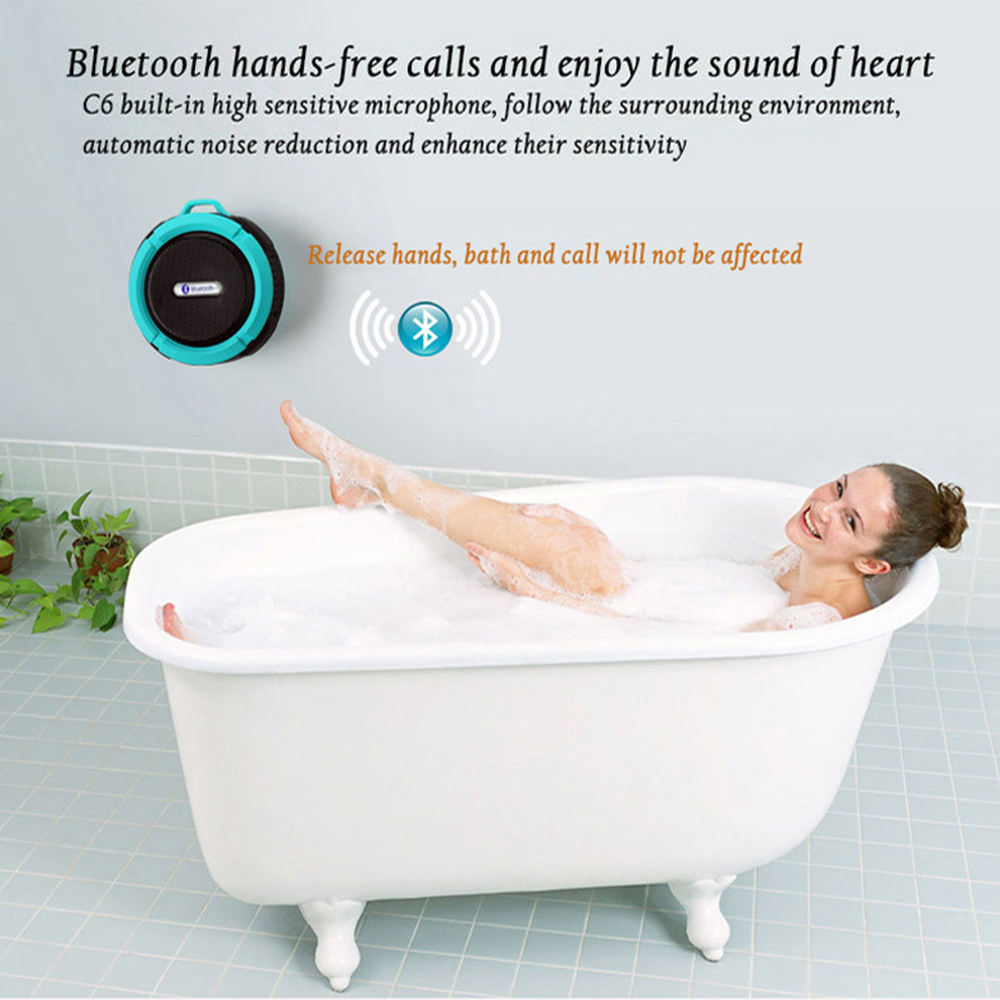 Woman smiling in a white clawfoot bathtub, with a blue Bluetooth speaker on the wall.