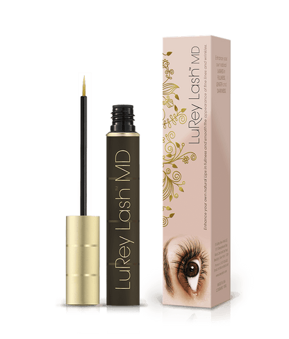 Gold-capped black mascara tube with fine brush beside a floral-patterned box featuring an eye.