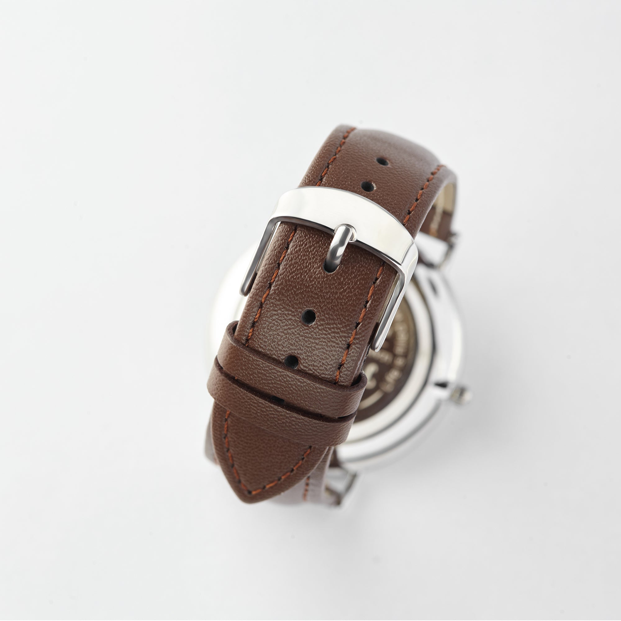 Close-up of a brown leather watch strap with a silver buckle against a white background.