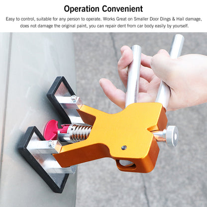 Hand using an orange dent puller with silver handles on a car surface.
