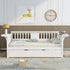 White daybed with slatted back, yellow lamp, clock on wall, deer art, and wicker basket on rug.