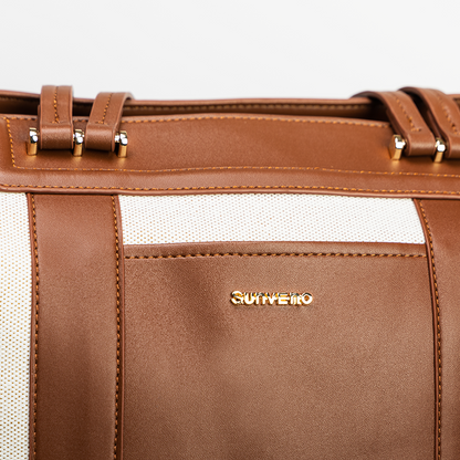 Brown leather bag with white fabric accents, gold hardware, and brand logo.