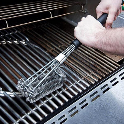 Hands using a bristle brush to clean a metallic grill grate.